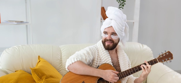 Joven con parches debajo de los ojos toca la guitarra en casa concepto de cosmetología para hombres y