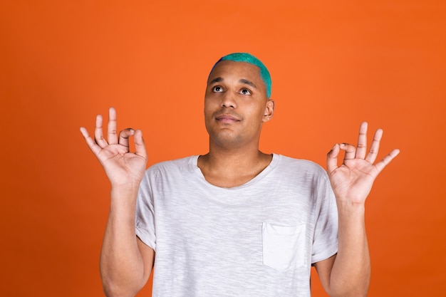 Joven en pared naranja meditar con gesto de yoga