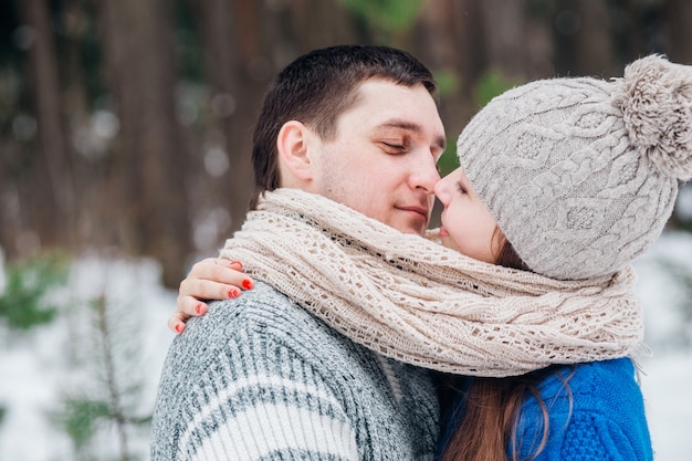 Foto joven pareja abrazándose y besándose en el bosque en invierno.