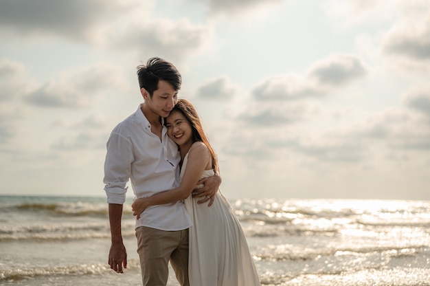 Joven pareja abrazándose en la playa en la puesta de sol.Verano enamorado, concepto de día de San Valentín.