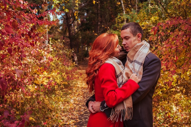 Joven pareja abrazos en el bosque de otoño entre