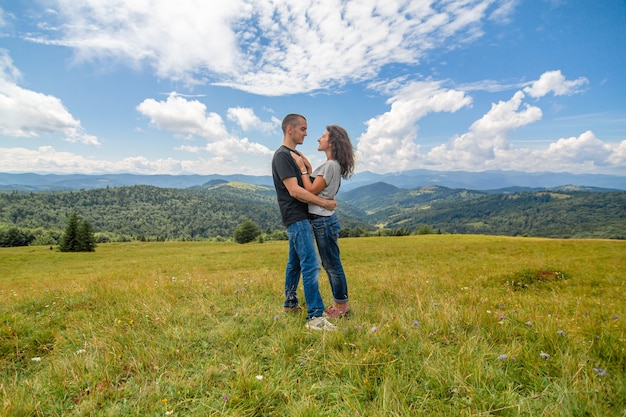 Joven pareja abrazos sobre fondo de paisaje de montaña increíble.