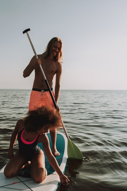 Foto joven pareja adolescente fila surf en mar con paleta.