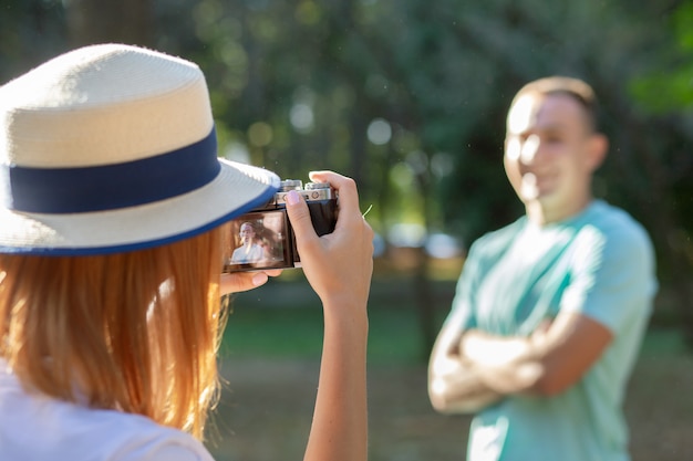 Joven pareja adolescente tomando fotos el uno al otro al aire libre en el soleado parque de verano.