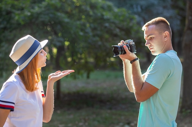 Joven pareja de adolescentes tomando fotografías el uno del otro al aire libre en el parque soleado de verano.