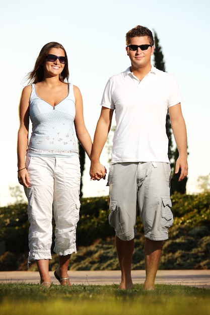 Una joven pareja agradable sonriendo y caminando en el parque