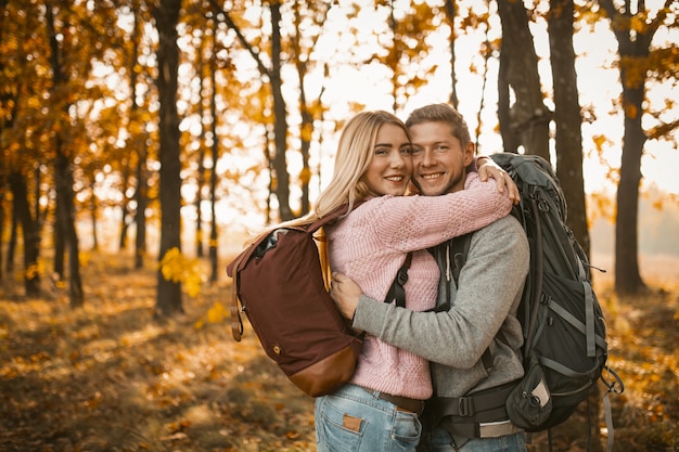 Joven pareja alegre abrazando en bosque del otoño