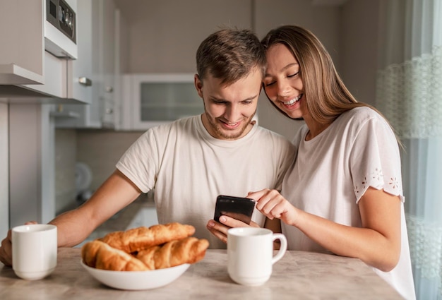 Joven pareja alegre con smartphone durante