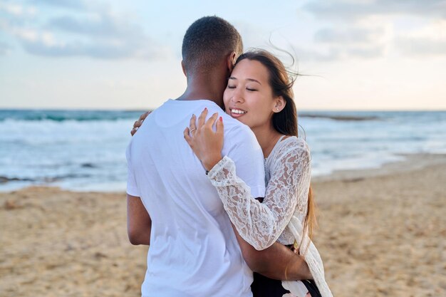 Joven pareja amorosa abrazándose en la playa