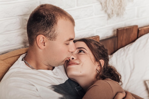 Joven pareja amorosa acostada en la cama abrazándose y pasando tiempo juntos