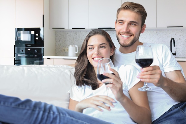 Joven pareja amorosa bebiendo una copa de vino tinto en su sala de estar