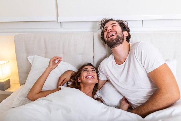 Joven pareja amorosa en la cama. Pareja joven acostado en la cama y riendo mientras se hacen cosquillas. Feliz pareja joven sensual acostado juntos en la cama por la mañana