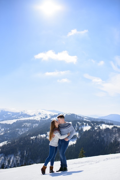 Joven pareja amorosa en una cita en la cima de una montaña nevada