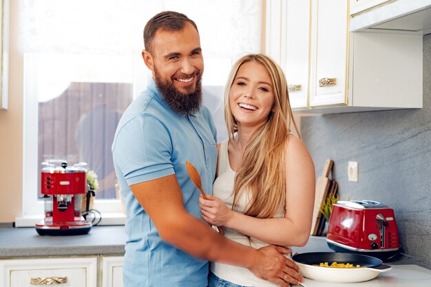 Joven pareja amorosa cocinando juntos en la cocina de casa