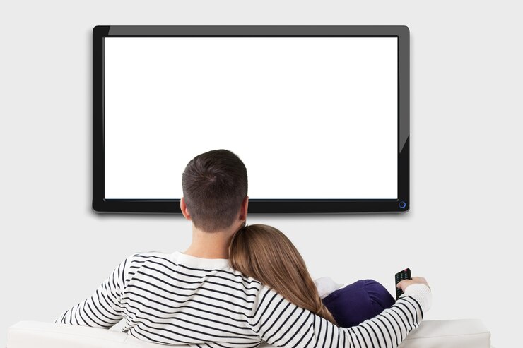 Foto joven pareja amorosa feliz sentado en el sofá en el interior y viendo la televisión.