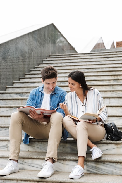 joven pareja amorosa increíble estudiantes colegas al aire libre afuera en pasos leyendo un libro escribiendo notas estudiando.