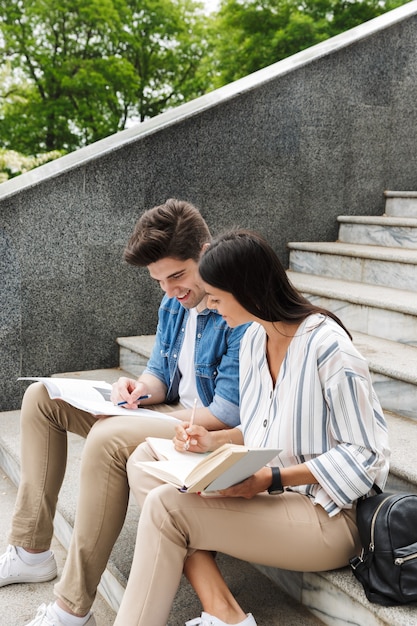 joven pareja amorosa increíble estudiantes colegas al aire libre afuera en pasos leyendo un libro escribiendo notas estudiando.