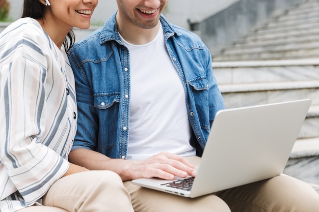 Joven pareja amorosa increíble gente de negocios colegas al aire libre afuera en pasos usando computadora portátil.