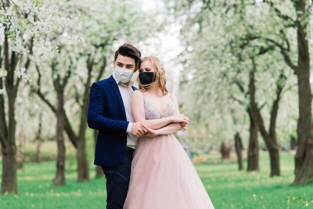 Joven pareja amorosa con mascarillas en el día de su boda