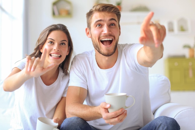 Joven pareja amorosa en el sofá en casa viendo la televisión y riendo