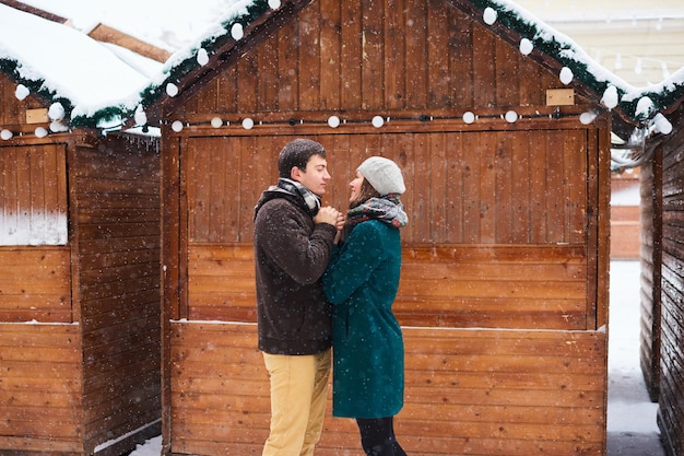 Una joven pareja amorosa vestida con bufandas a cuadros camina por la ciudad vieja en invierno