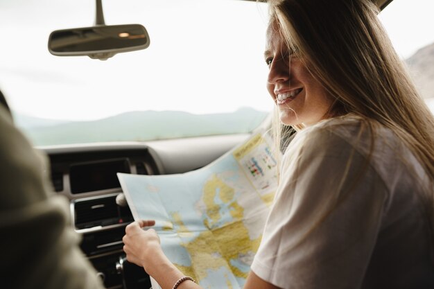 Joven pareja amorosa en un viaje por carretera con mapa dentro de un coche
