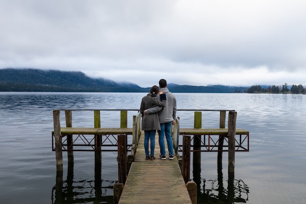 Joven pareja asiática abrazando apoyándose en el hombro en el puente del lago Te Anau, Nueva Zelanda