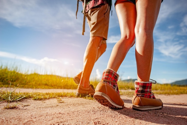 Joven pareja asiática en un amplio campo está caminando a pie para explorar el bosque como una actividad de vacaciones en la temporada de otoño del camino forestal. Senderismo, excursionista, equipo, bosque, camping, concepto de actividad.