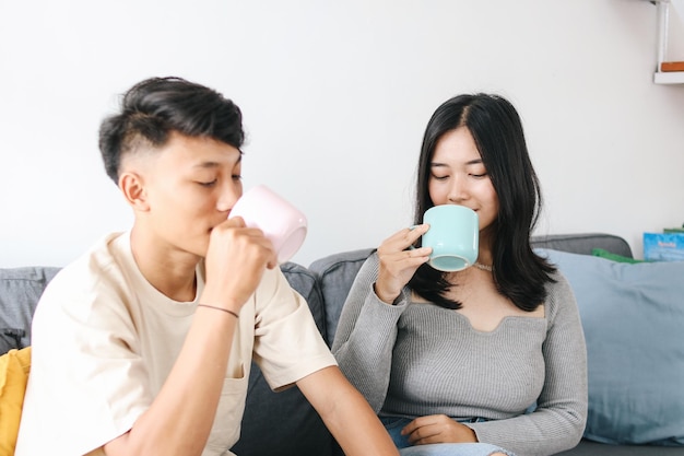 Una joven pareja asiática bebe agua juntos en la sala de estar