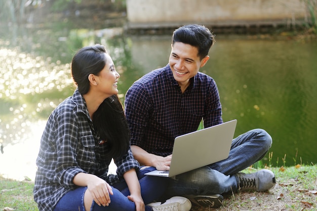 Joven pareja asiática divirtiéndose con el portátil