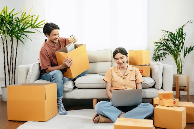 Joven pareja asiática inteligente empresarios propietarios de pymes rodeados de cajas en línea trabajando desde casa