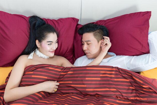 Foto joven pareja asiática mirando los ojos juntos en la cama