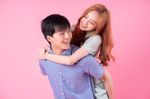 Joven pareja asiática posando sobre fondo rosa