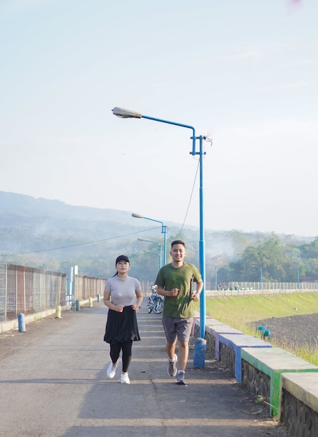 Joven pareja asiática en ropa deportiva corriendo juntos por la mañana