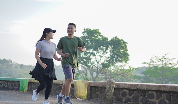 Joven pareja asiática en ropa deportiva corriendo juntos por la mañana