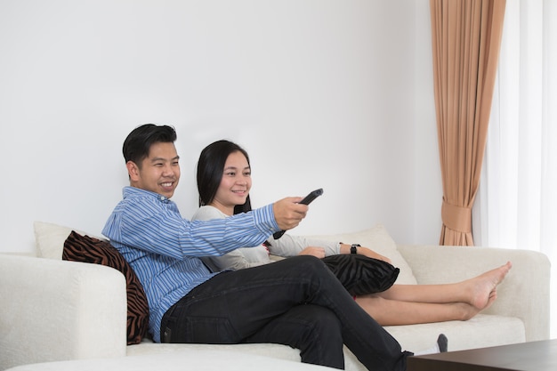 Joven pareja asiática viendo la televisión juntos en el sofá