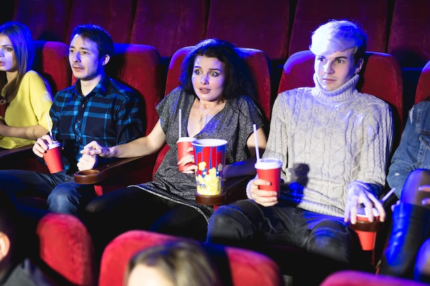 Joven pareja asustada en el cine viendo una película de terror