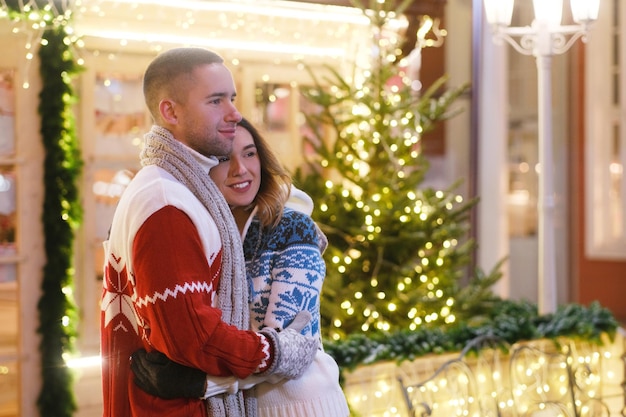 Joven pareja atractiva pasando tiempo juntos el día de Navidad cerca del árbol de Navidad.