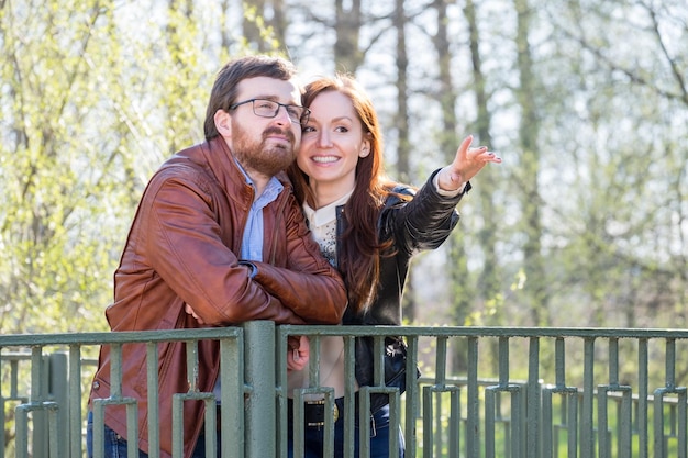 Joven pareja atractiva en el puente en el parque en un día soleado