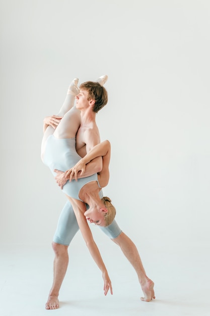 Joven pareja de bailarines de ballet moderno posando sobre fondo blanco de estudio