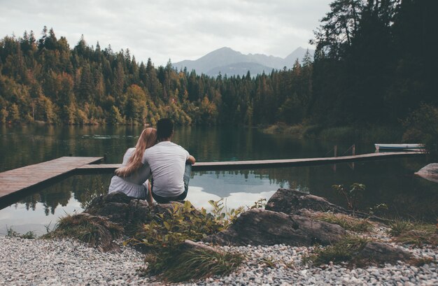 Joven pareja besándose en frente hermoso paisaje del lago