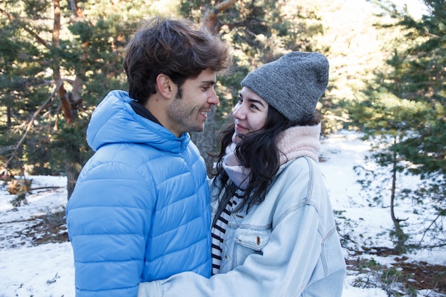 Joven pareja besándose en las montañas en un día nevado.