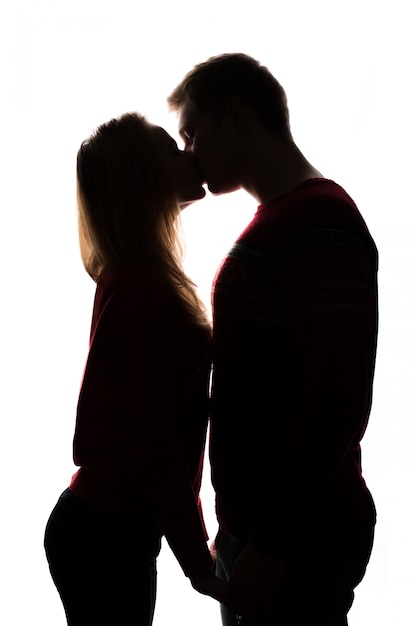 Foto joven pareja besándose. silueta aislada en el fondo blanco. concepto de san valentín