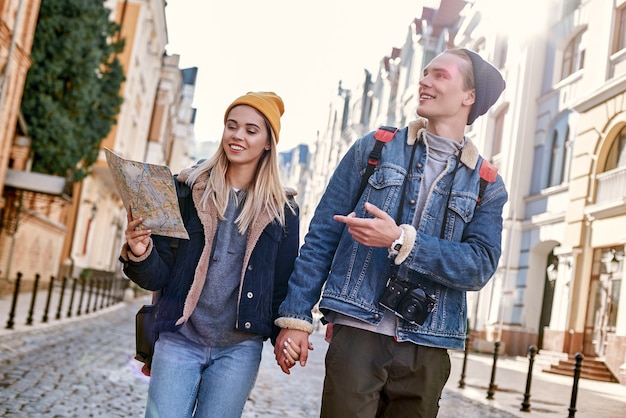 Una joven pareja de blogueros de viajes intenta navegar por mapa en una ciudad desconocida