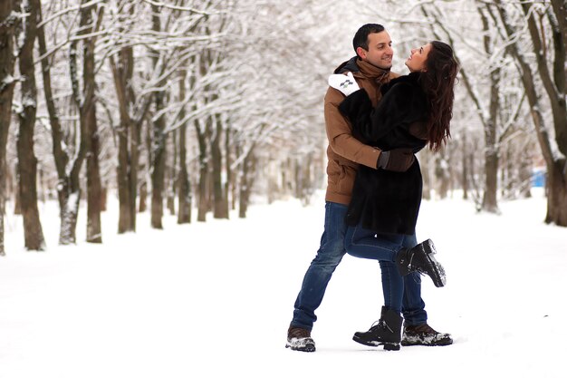 Una joven pareja camina en un parque de invierno al aire libre