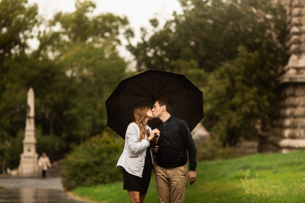 Joven pareja caminando en el parque en un día lluvioso. historia de amor en budapest