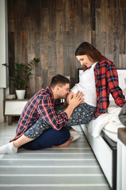 Una joven pareja casada esperando un bebé. Hermosa pareja acostada en el dormitorio hace planes para el nacimiento de un bebé. Primer hijo, posparto, familia joven.