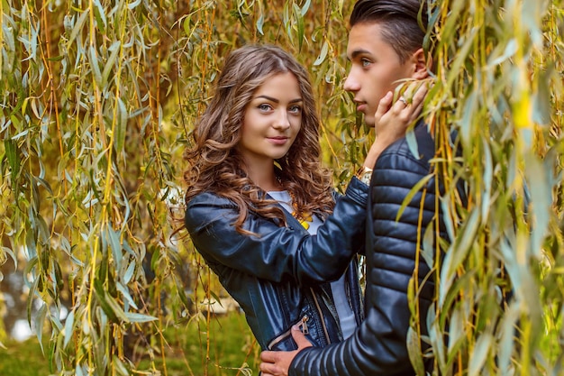 Joven pareja casual disfruta el uno del otro bajo un árbol verde.