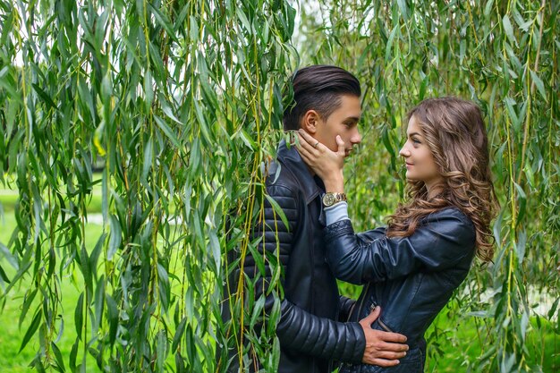 Joven pareja casual de hombres y mujeres bajo un árbol verde.