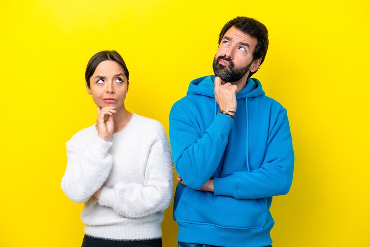 Foto joven pareja caucásica aislada de fondo amarillo de pie y pensando en una idea